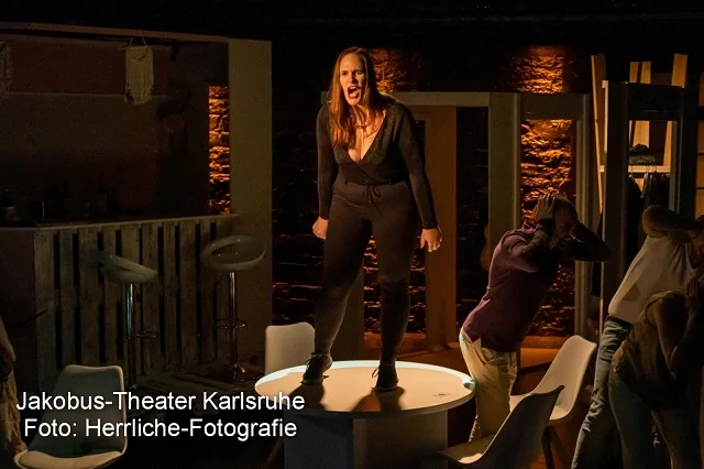 Theaterstück Der Spieleabend Frau schreit auf Tisch Theaterstück Der Spieleabend Frau schreit auf Tisch